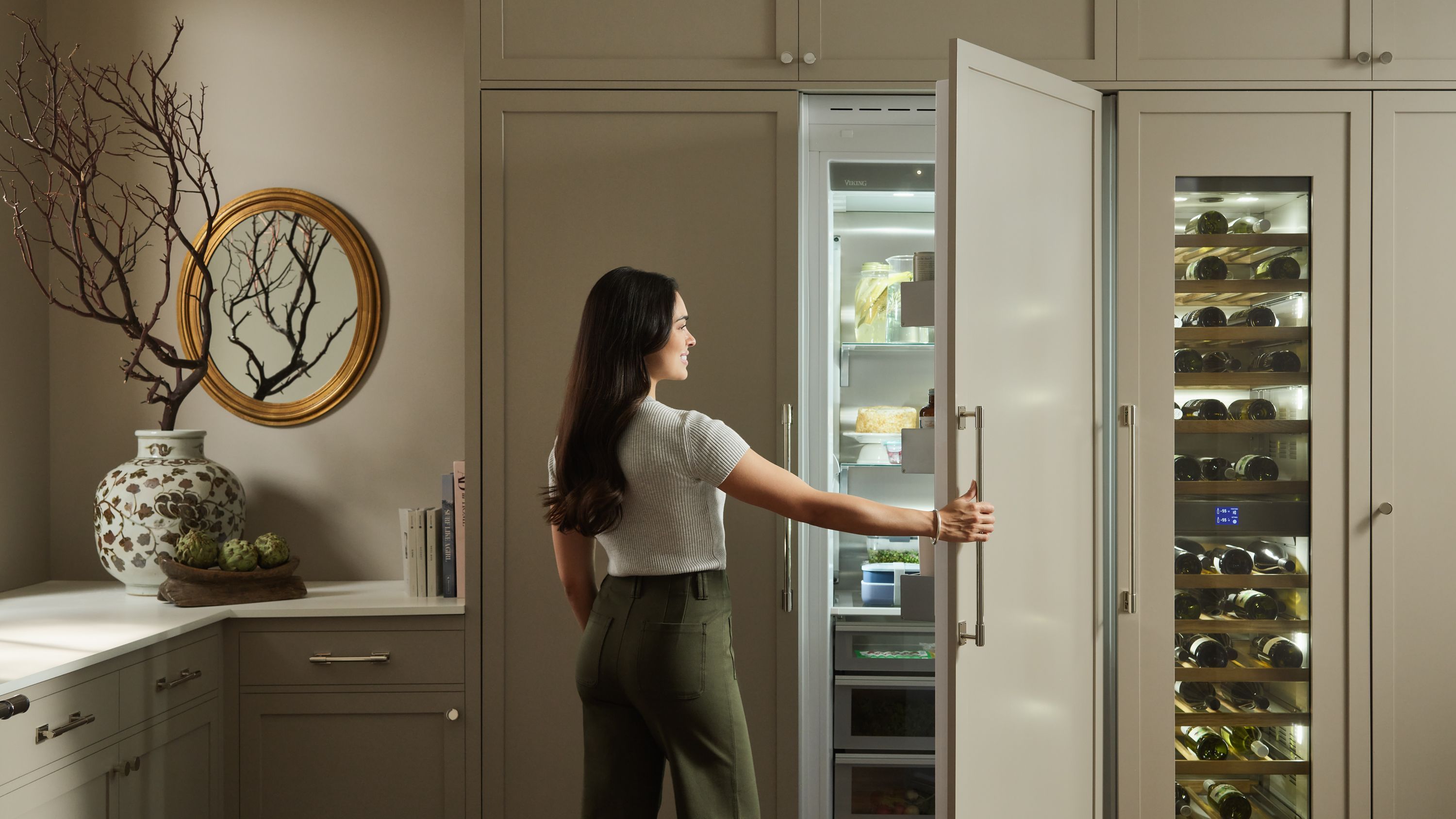 Woman standing in front of an open refrigerator, integrated into the cabinetry of the kitchen