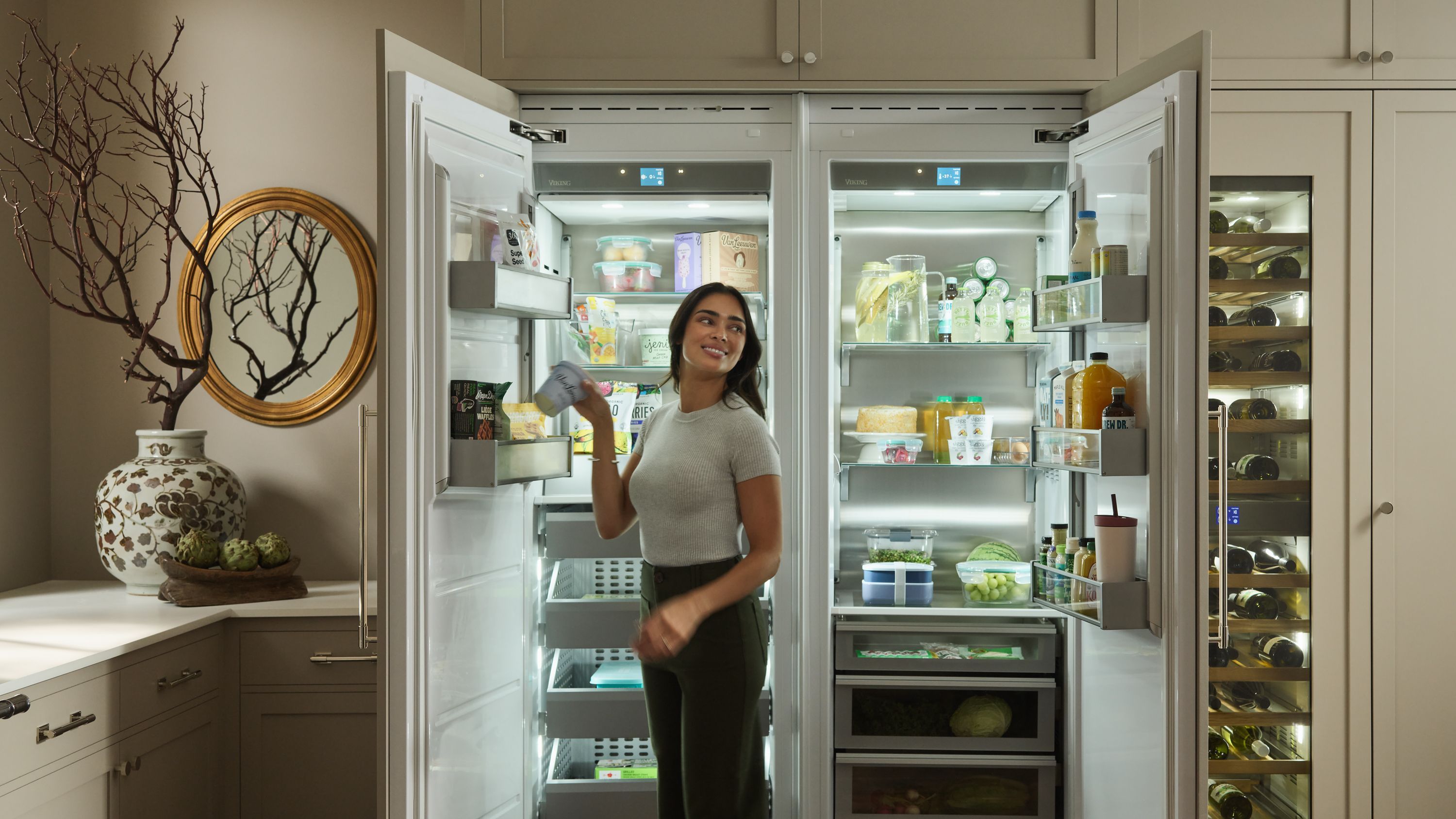 Woman standing in front of an open french door refrigerator, integrated into the kitchen cabinetry
